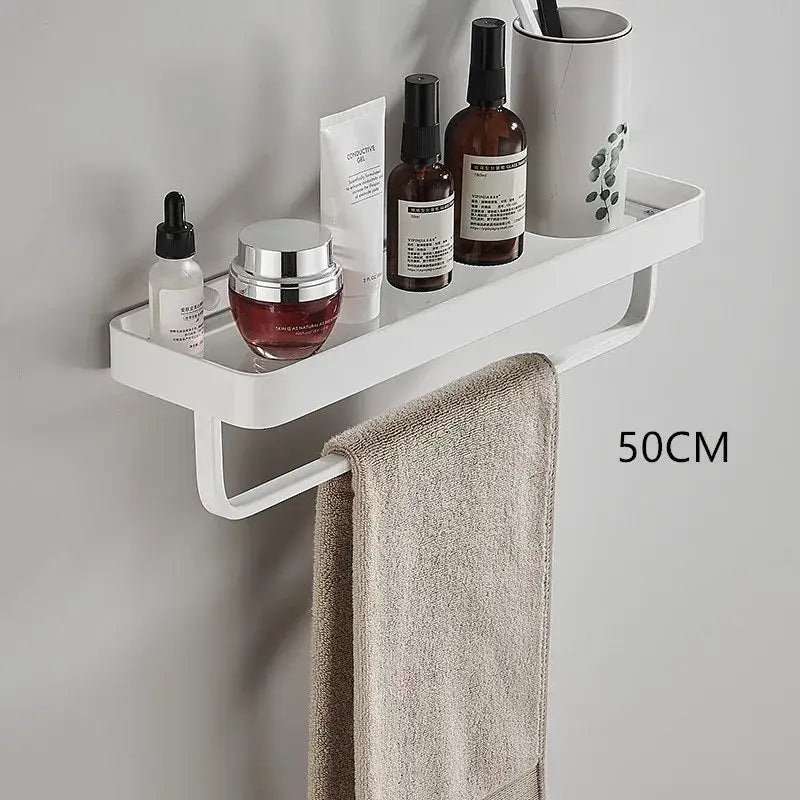 White double tier glass corner shelf with towel bar mounted on wall holding toiletries and beige towel