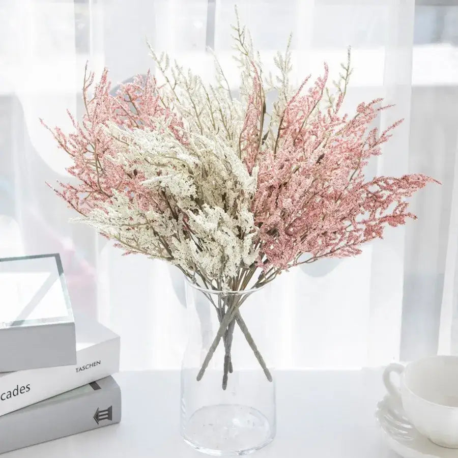 A delicate lavender bouquet of dried pink and white baby’s breath flowers in a clear glass paper box vase