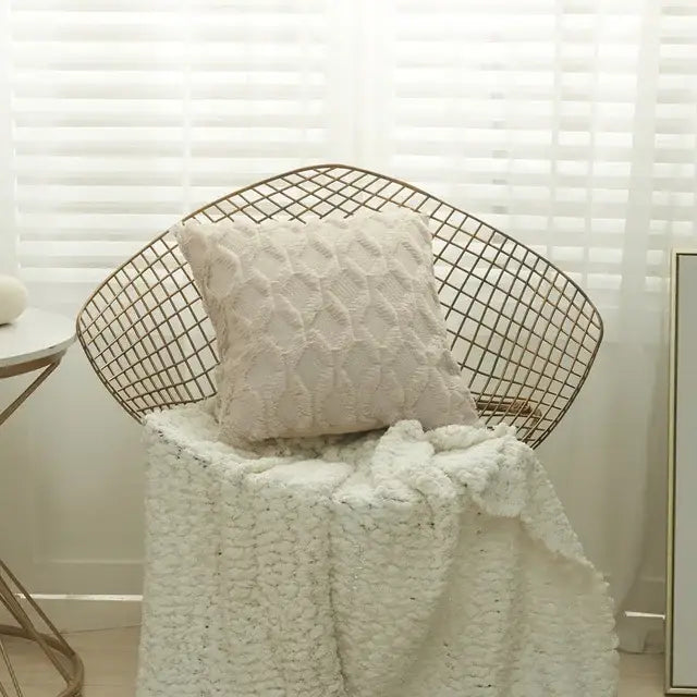 Cream-colored textured knit white embroidered diamond cushion cover resting on wireframe chair for living room decor