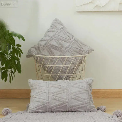 Gray textured throw pillows with geometric knit pattern and tassels as a white embroidered diamond cushion cover for decor