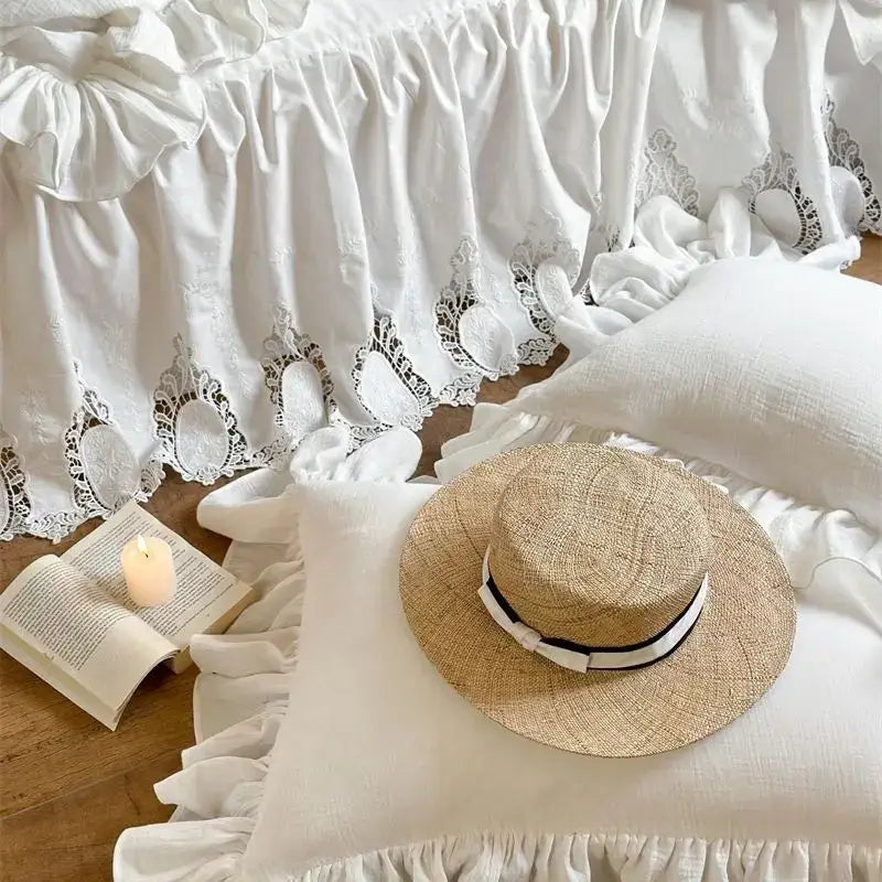 A woven straw hat with a black and white ribbon band displayed alongside a white embroidered lace cotton ruffles bedding set