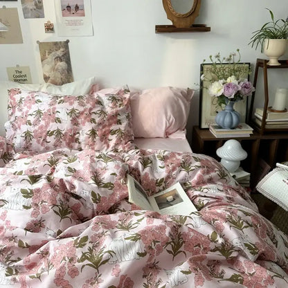 Pink floral duvet cover set with delicate blossoms and green leaves on white embroidered cotton fabric for bedroom bedding