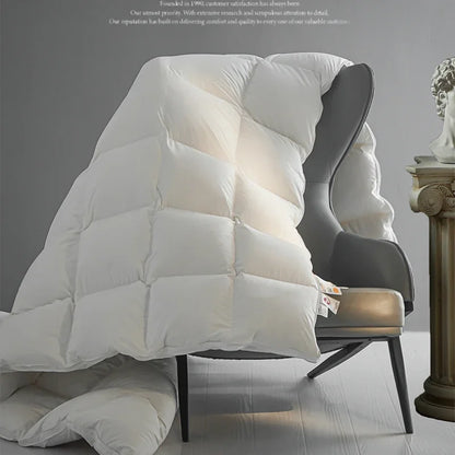 White quilted goose down autumn winter duvet draped over a modern chair showing thick warm velvet quilt