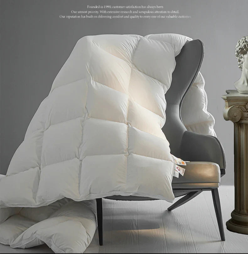 White quilted goose down comforter draped over modern armchair thick warm velvet autumn winter quilt