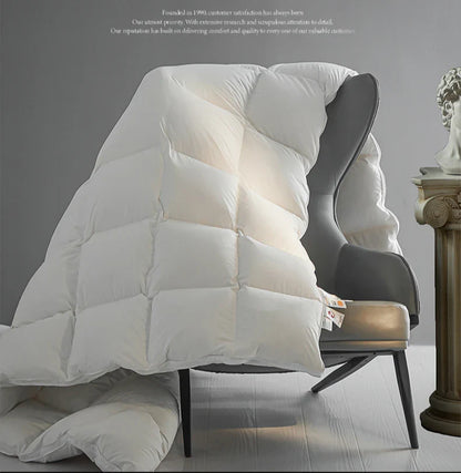 White quilted goose down comforter draped over modern armchair thick warm velvet autumn winter quilt