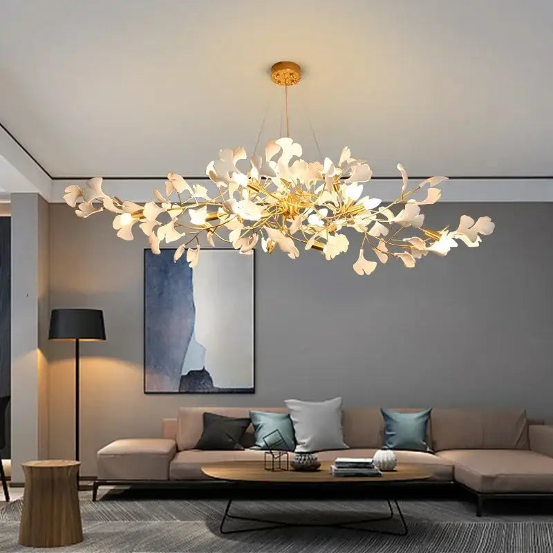 A modern gold-toned decorbites ginkgo chandelier with white leaf accents pendant light for living room use