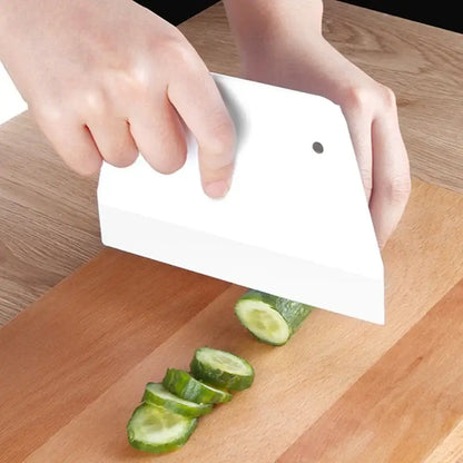 White plastic cream cake cutter spatula with small black dot slicing cucumbers for dough cream cake preparation