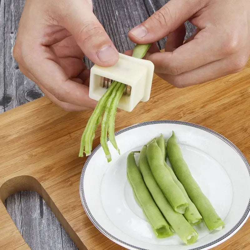 White plastic green bean slicer with metal blades and multiple slots for slicing green beans in the kitchen