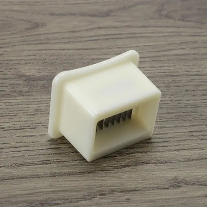 Off-white plastic green bean slicer with rectangular body and five metal tines for efficient bean shredding