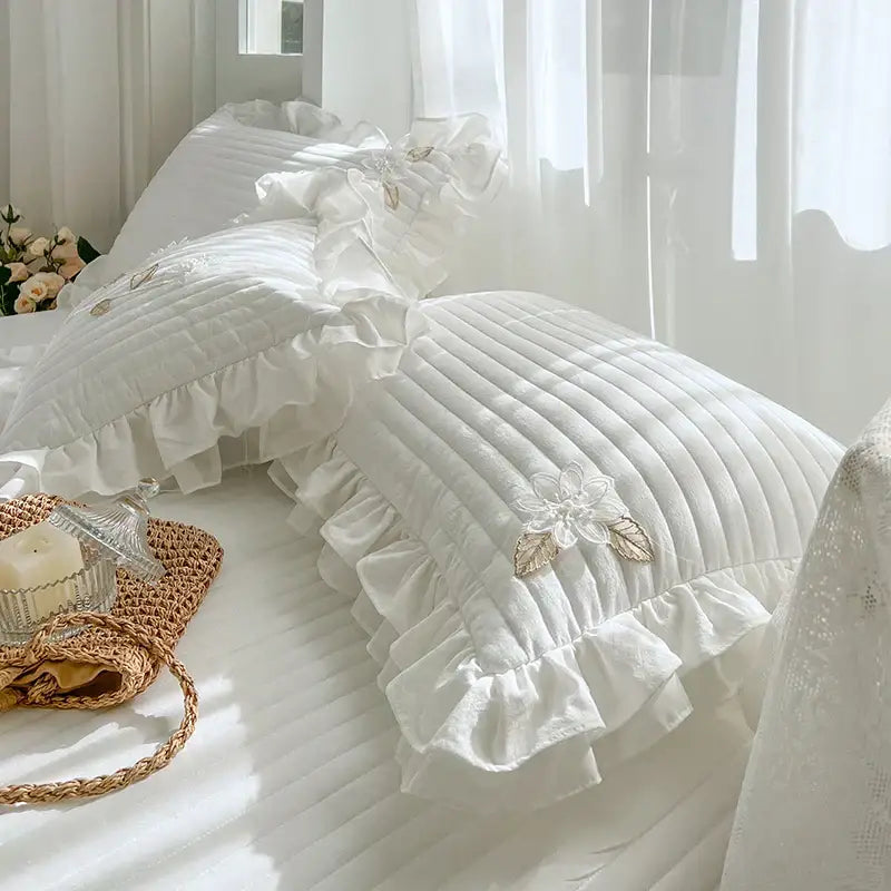 White quilted bedspread coverlet with ruffled edges and delicate embroidered floral appliqués for bedroom use