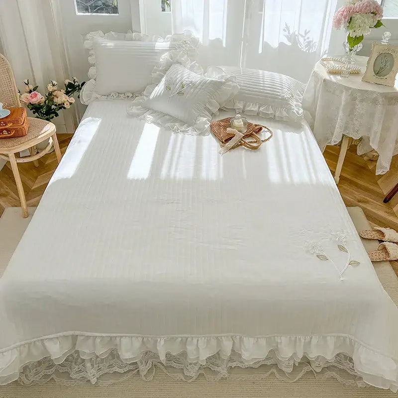 White quilted bedspread coverlet with delicate ruffled edges lace trim and subtle embroidered floral details