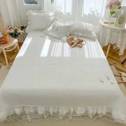 White quilted bedspread coverlet with delicate ruffled edges lace trim and subtle embroidered floral details
