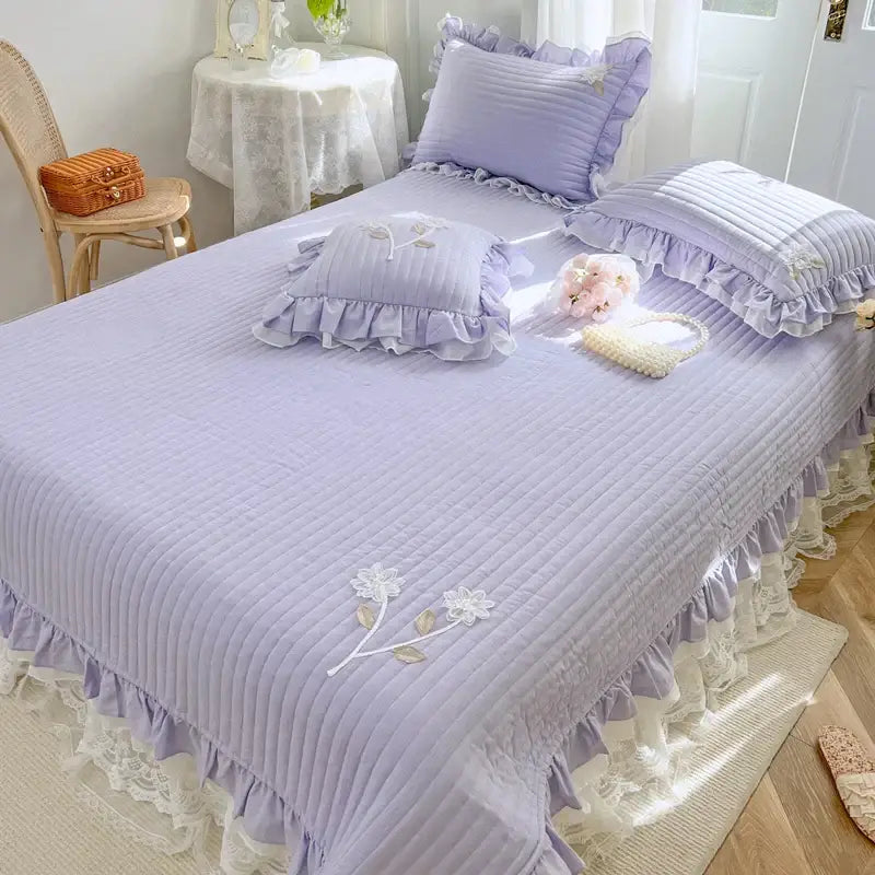 Lavender quilted bedspread coverlet with delicate ruffled edges and embroidered white floral lace details for bedroom decor