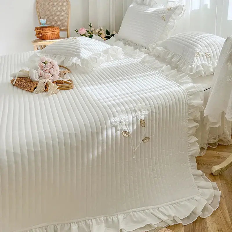 White ruffled quilted bedspread coverlet with delicate floral embroidery and ribbed texture for elegant bedroom decor