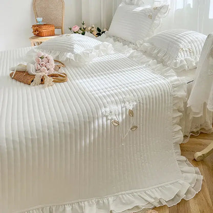 White ruffled quilted bedspread coverlet with delicate floral embroidery and ribbed texture for elegant bedroom decor