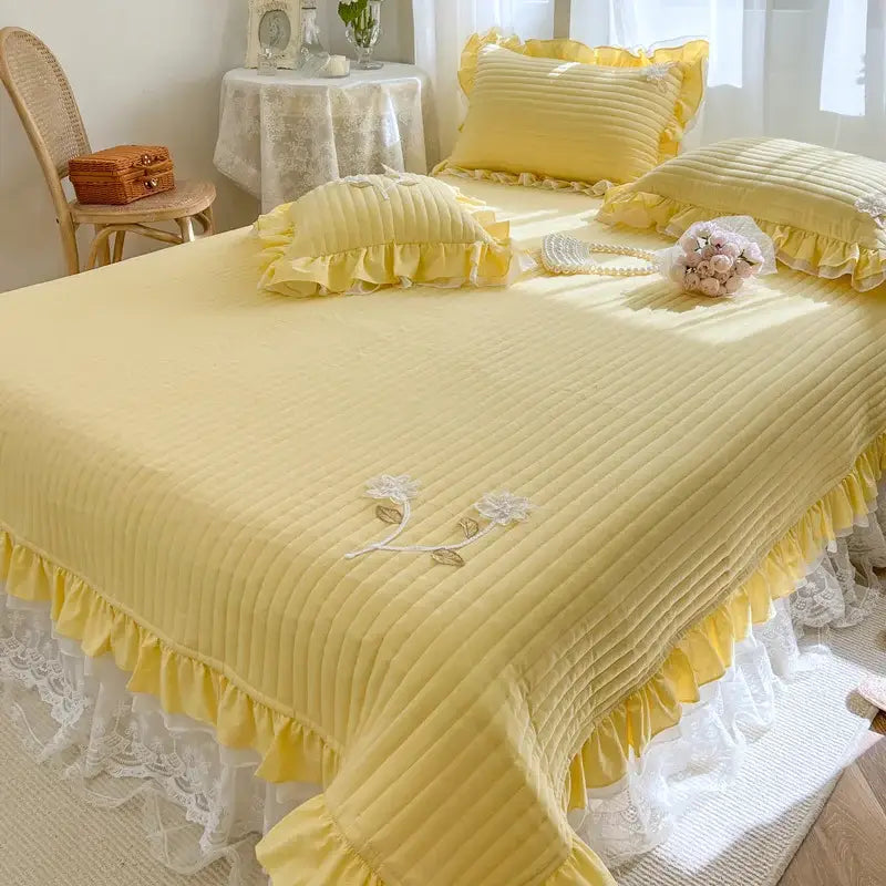 Yellow quilted bedspread coverlet with ruffled edges and embroidered floral details for elegant bedroom decor