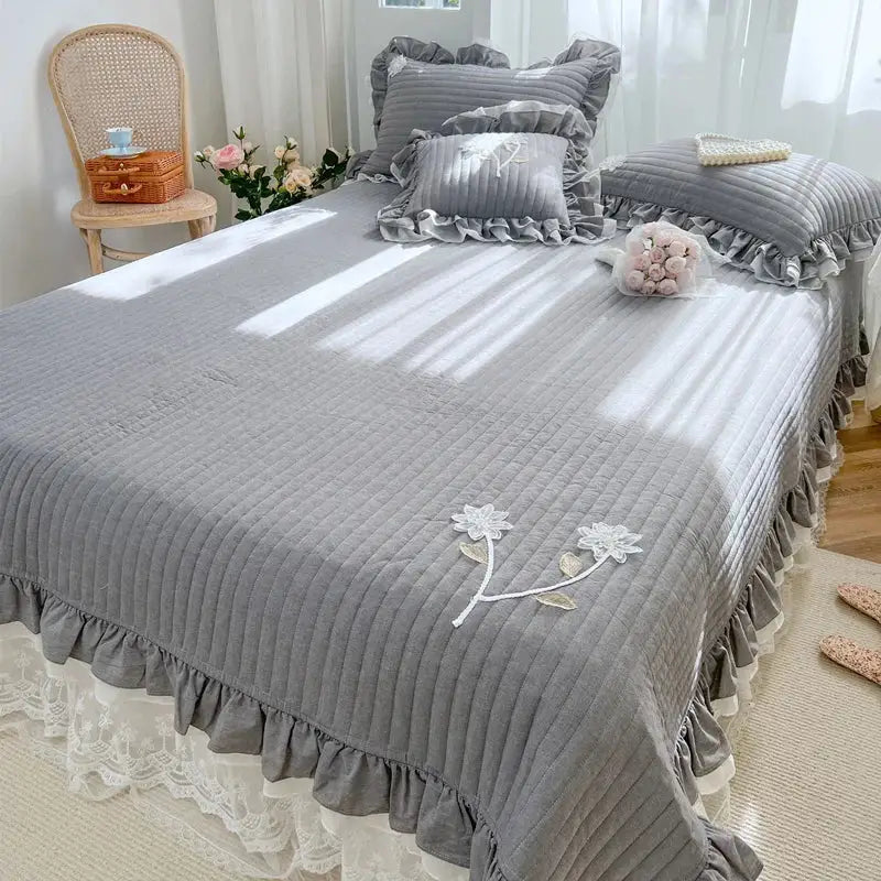 Gray quilted bedspread coverlet with white floral embroidery and ruffled edges for bedroom decor