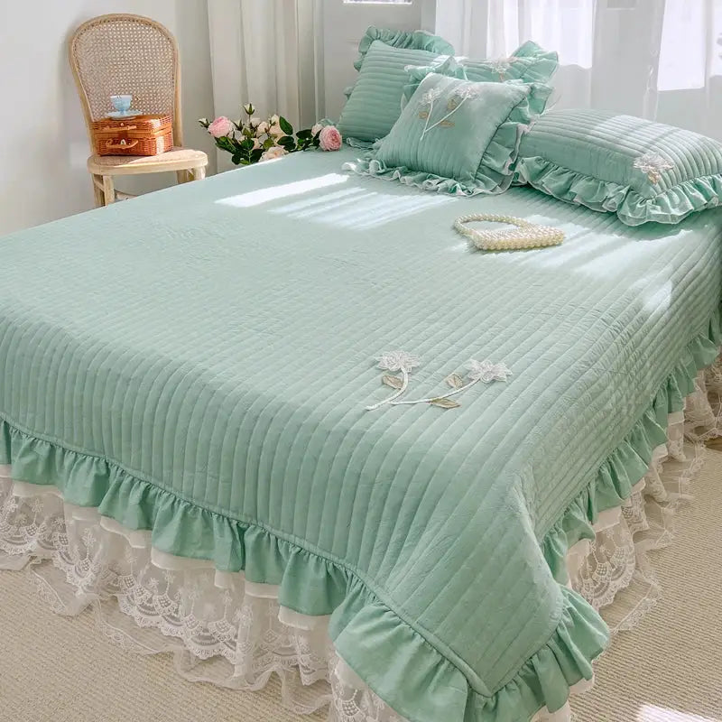 Mint green quilted bedspread coverlet with delicate white lace trim and embroidered floral details for bedroom use