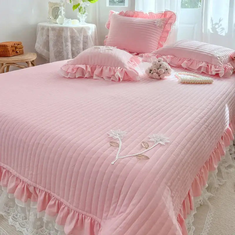 Pink quilted bedspread coverlet with ruffled edges and white floral lace embroidery for bedroom use