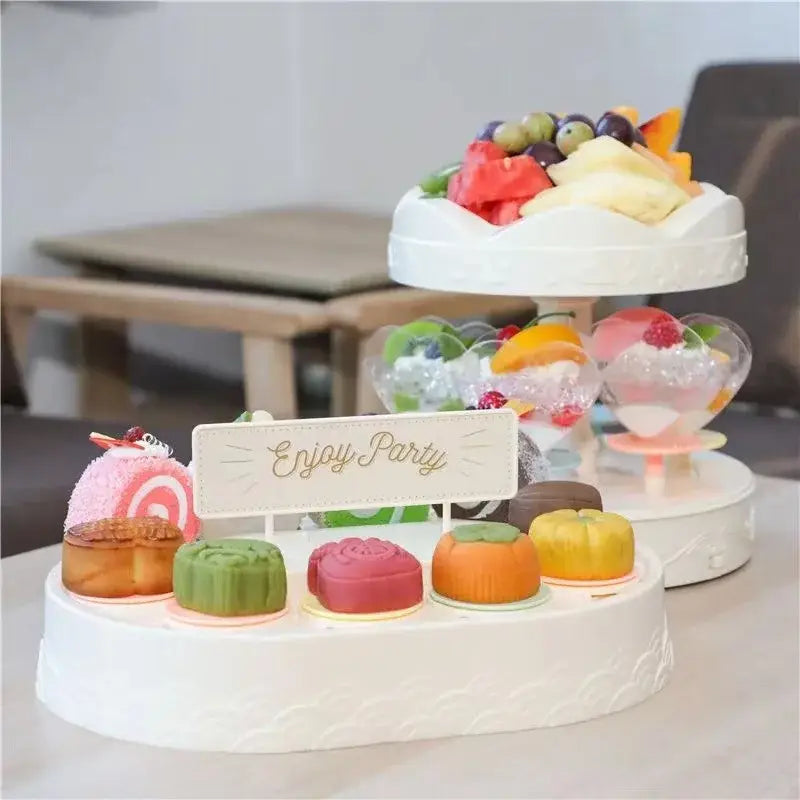 White two tiered rotating dessert table with scalloped edges and enjoy party sign for sushi machine dining room use