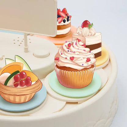 A whimsical cream-colored cupcake with pink frosting on a mint-green plate featured on a white two tiered rotating dessert table sushi machine