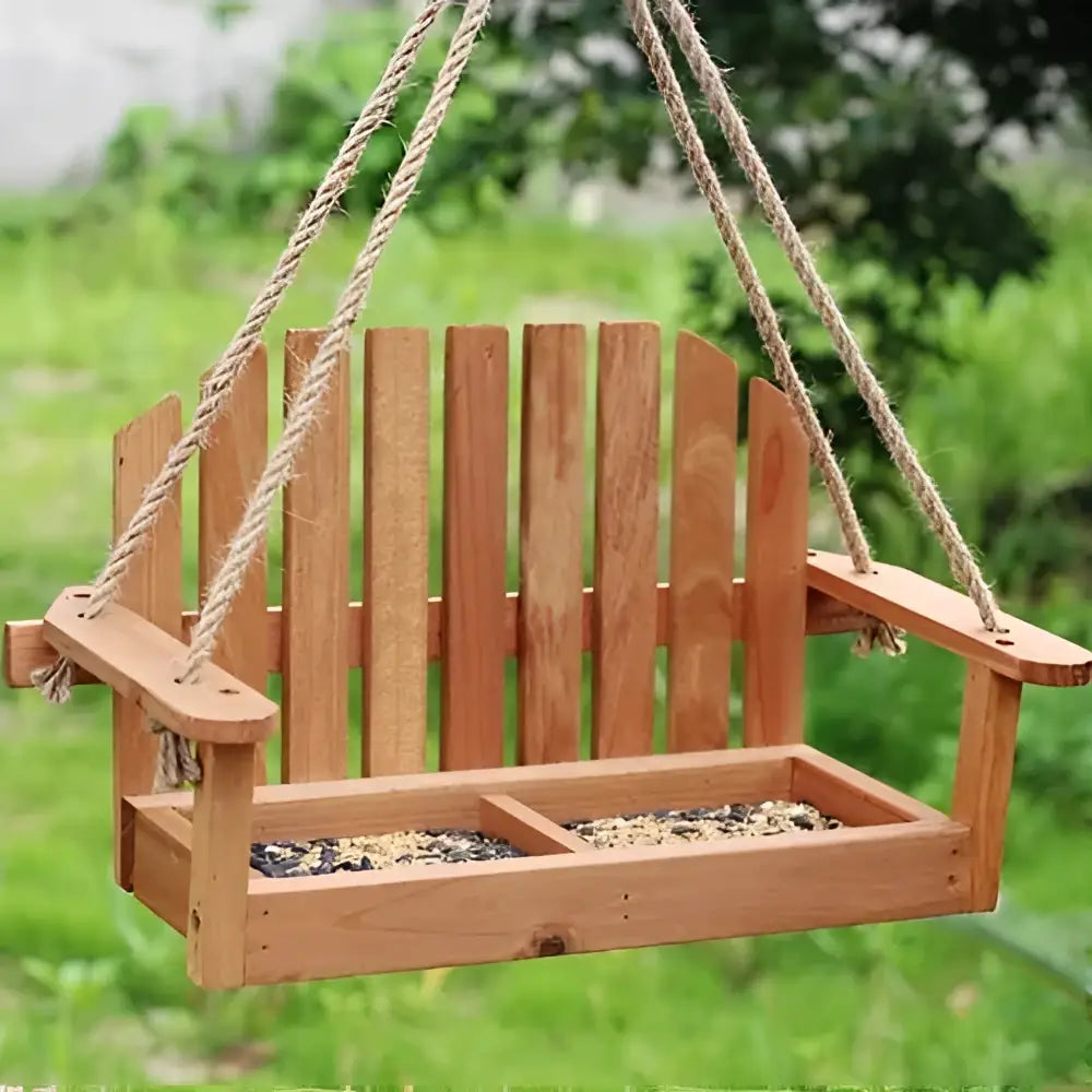 Light brown wooden bird feeder chair with slatted back and divided tray filled with seeds for garden decor
