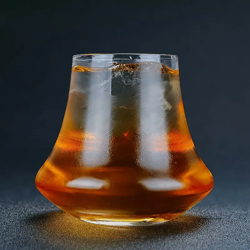 A clear fluted decorbites crystal whiskey glass tumbler filled with amber liquid and ice for dining room spirits