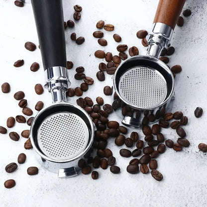 Two stainless steel coffee filters with wooden and black bottomless portafilter handles surrounded by roasted coffee beans
