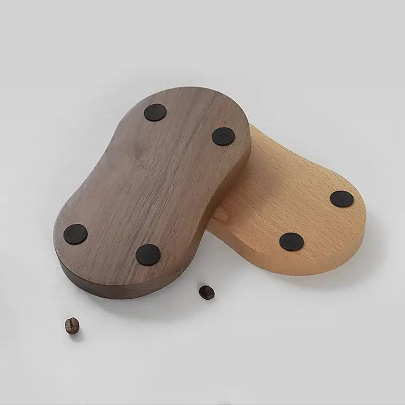 Two wooden espresso distributor tampers in dark walnut and light oak with black circular adhesive pads for stability