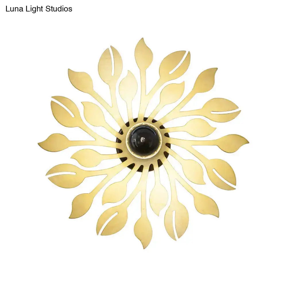 Gold-toned wooden floral wall lamp with leaf pattern and central black bulb housing for orange and yellow bedrooms