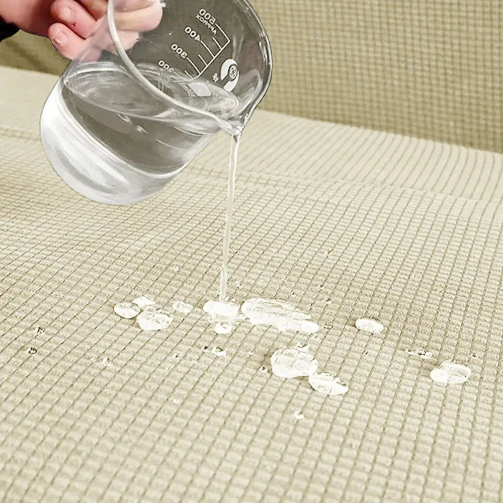 Clear glass measuring cup pouring water on beige textured mat demonstrating woven brown and cream modular sofa cover protection