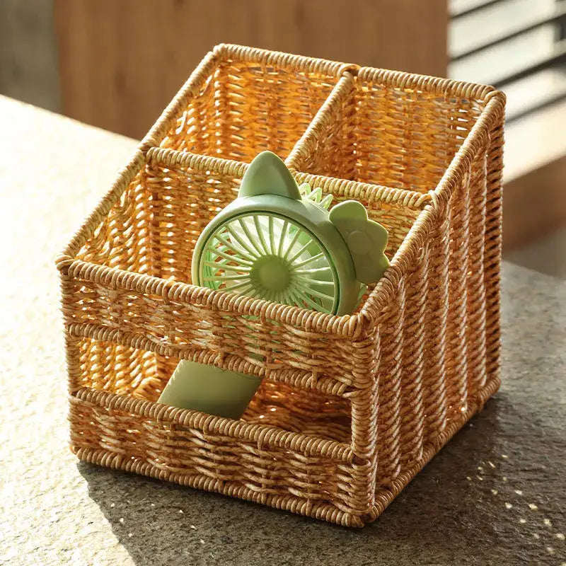A light green cat-ear handheld fan inside a woven tan desktop tissue box pen holder for living room organization