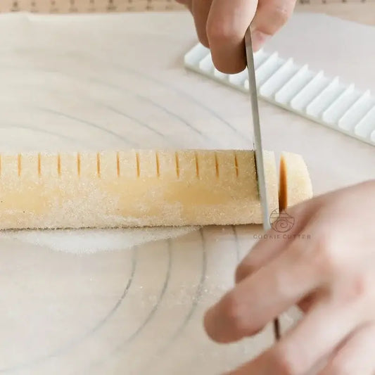 Yellow biscuit cake rolling mold with scale ruler slicing pale yellow rolled dough for decorbites biscuit cake rolling