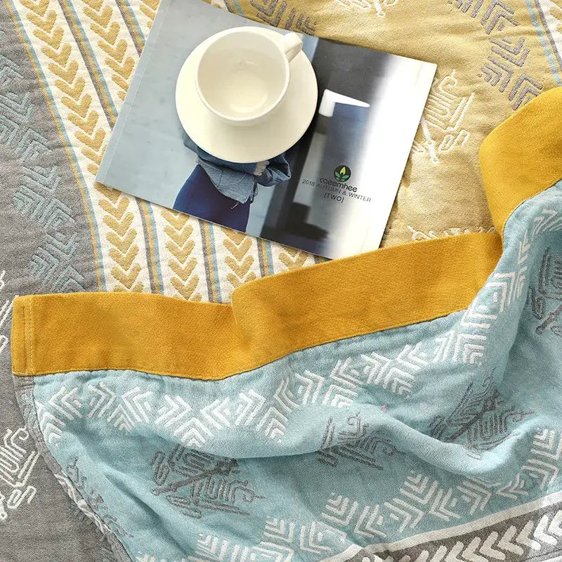 A light blue cotton stripe gauze towel quilt with a geometric pattern and mustard yellow trim for summer bedrooms