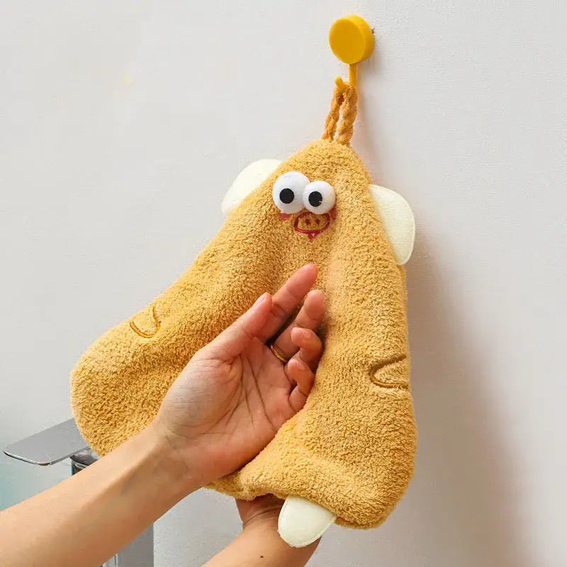 Yellow cartoon pig plush hand towel with white ears and googly eyes hanging from a hook for bathroom or kitchen decorbites cartoon pig