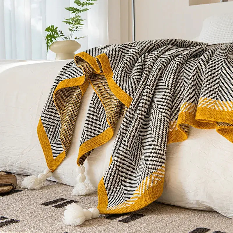 A cozy decorbites knitted diagonal sofa blanket with black and white diagonal stripe and yellow edge for living room decor