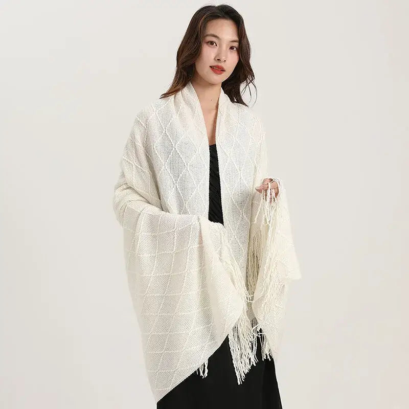 A soft off-white decorbites knitted diamond blanket shawl wrap with diamond pattern and long fringe for bedroom use