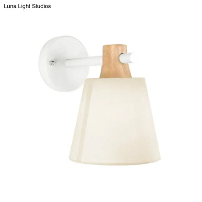 Minimalist yellow macaron fabric wall light with white circular base wood accent arm and cream tapered shade bedroom sconce
