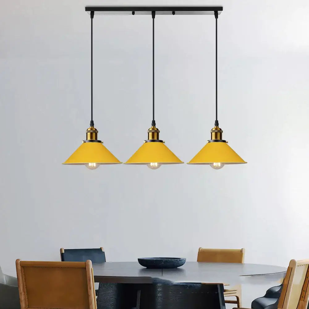 Three vibrant yellow conical pendant lights with brass fixtures hang on a black bar for colorful nordic decorbites decor
