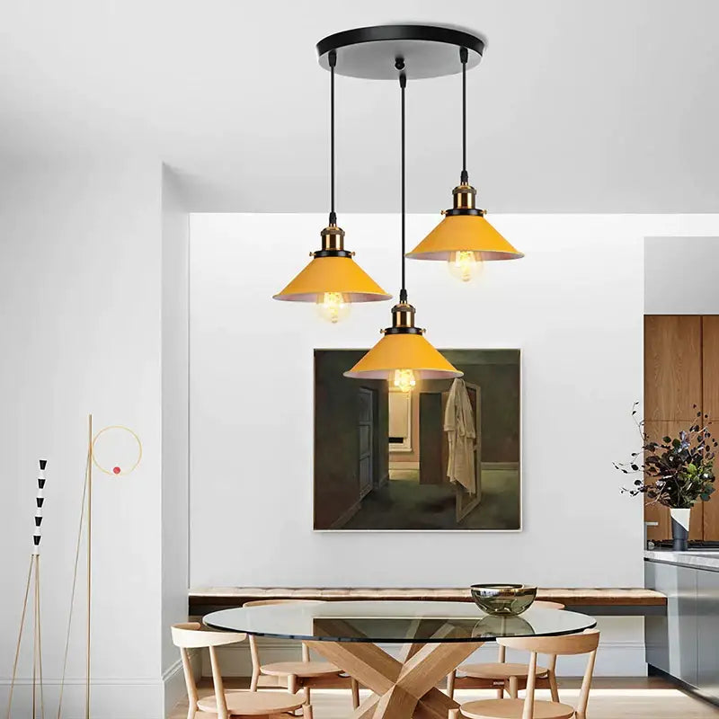 Set of three yellow nordic pendant lights with warm brass accents hanging from a black ceiling fixture by decorbites colorful nordic pendant
