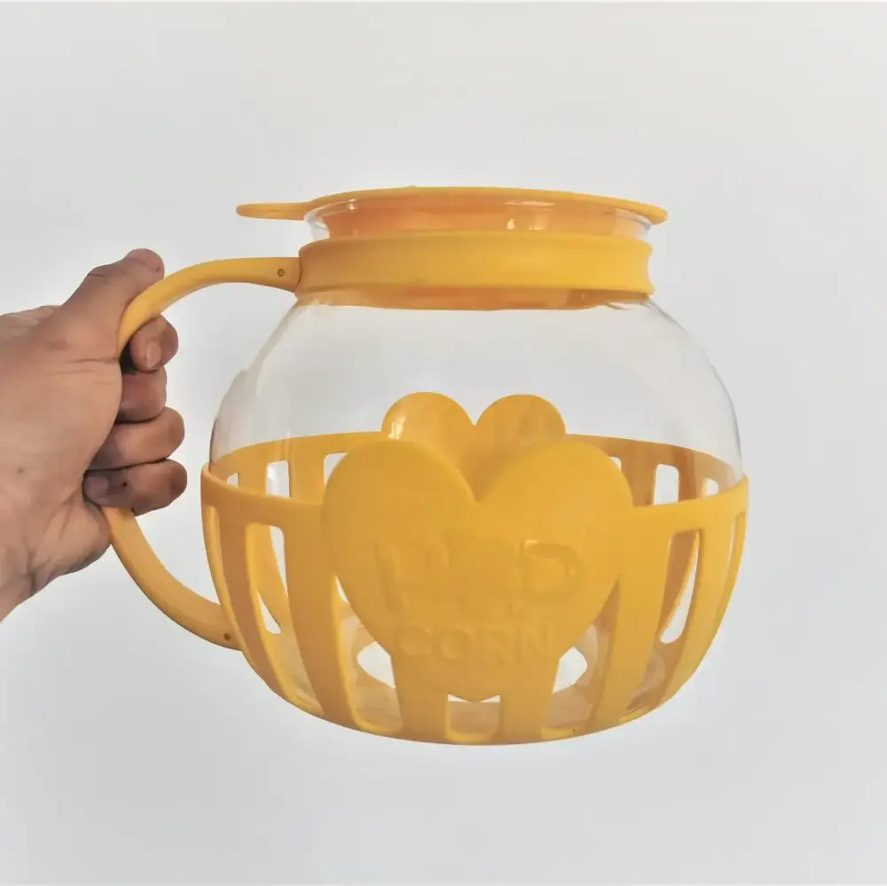 Yellow silicone heart-shaped protective sleeve with clear glass glass popcorn maker featuring handle and lid