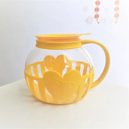 Yellow heart-shaped silicone protective sleeve with clear glass popcorn maker and matching yellow lid for kitchen use
