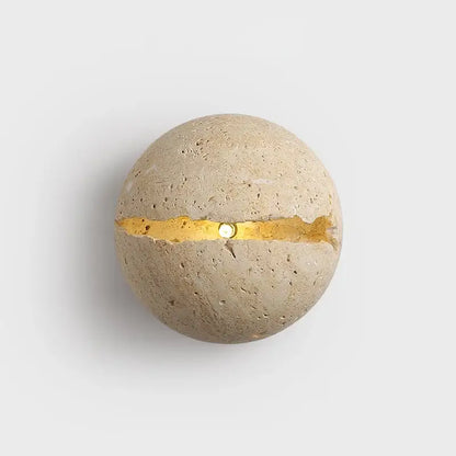 A spherical yellow travertine dino egg stone wall lamp with beige textured surface and gold accent for decorbites dino egg