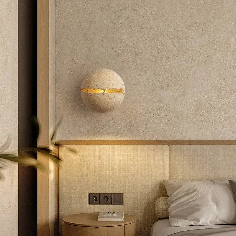 Beige yellow travertine dino egg stone wall lamp with a horizontal gold accent strip by decorbites for bedroom decor