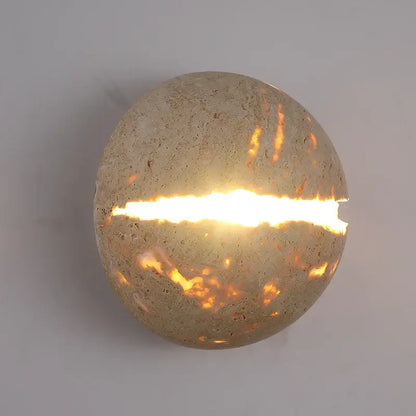 Yellow travertine dino egg stone wall lamp with textured concrete sconce and glowing horizontal slit for bedroom decorbites dino egg