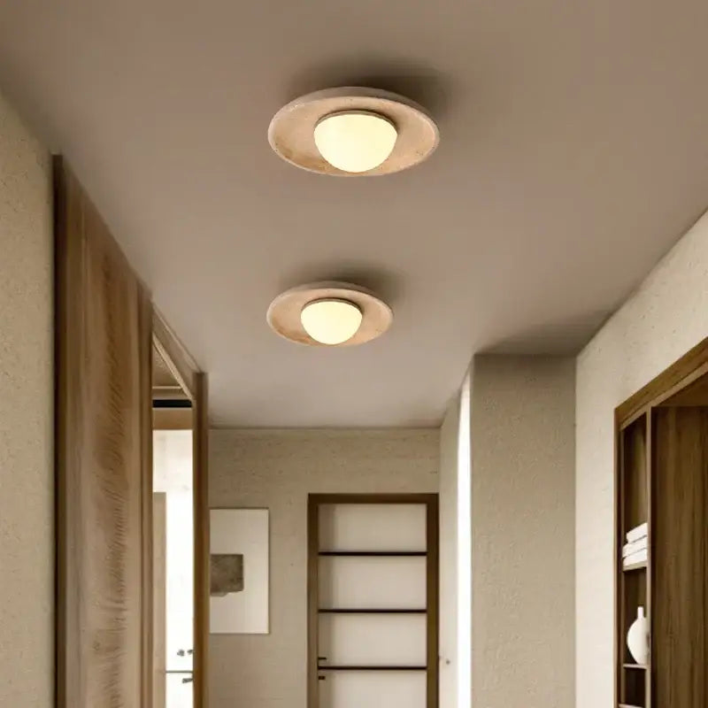 Two circular recessed led ceiling lamps with yellow travertine textured rings and warm frosted glass glow for living room