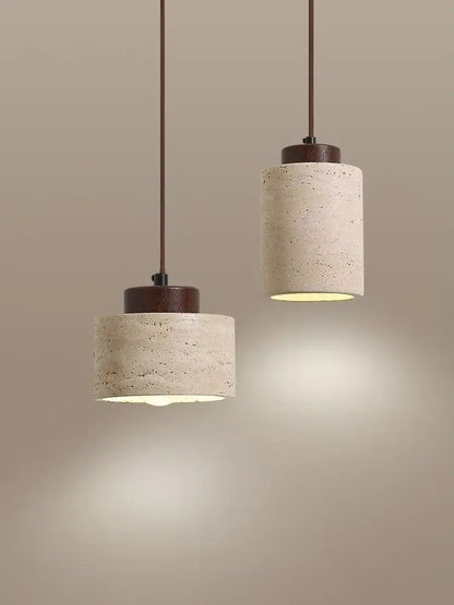 Two cylindrical concrete pendant lights with dark brown wooden tops complement a yellow travertine stone pendant light